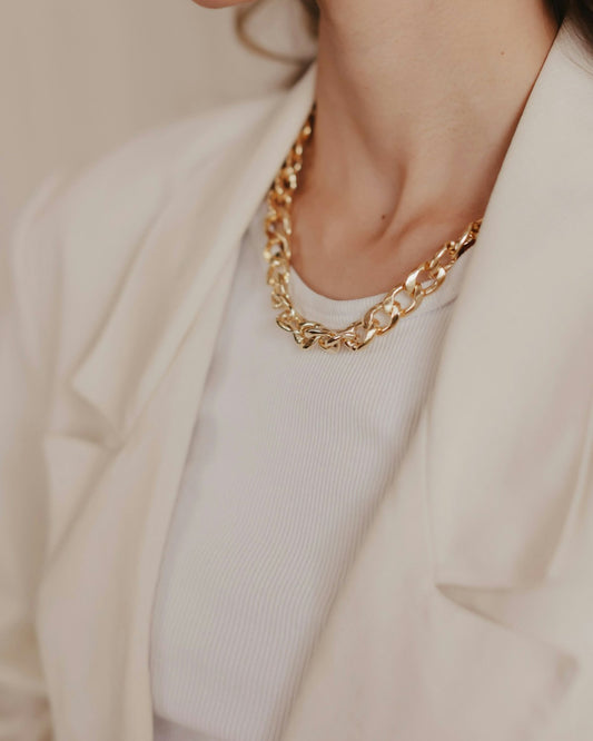 Collier maille dorée porté avec une veste blanche 3